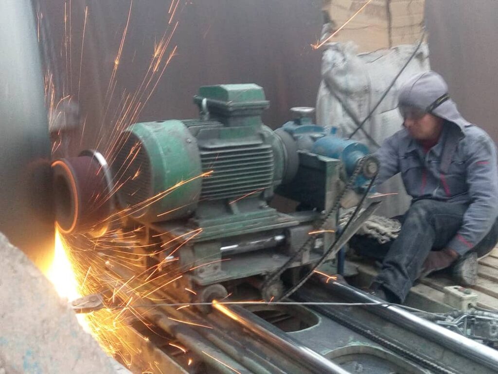 Specialist performing side surface grinding of a rotary kiln tire for precise alignment.