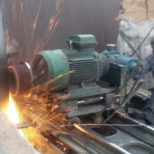 Grinding machine and operator performing precise surface grinding on rotary kiln components. Wear diagnosed by ho kiln alignment service.