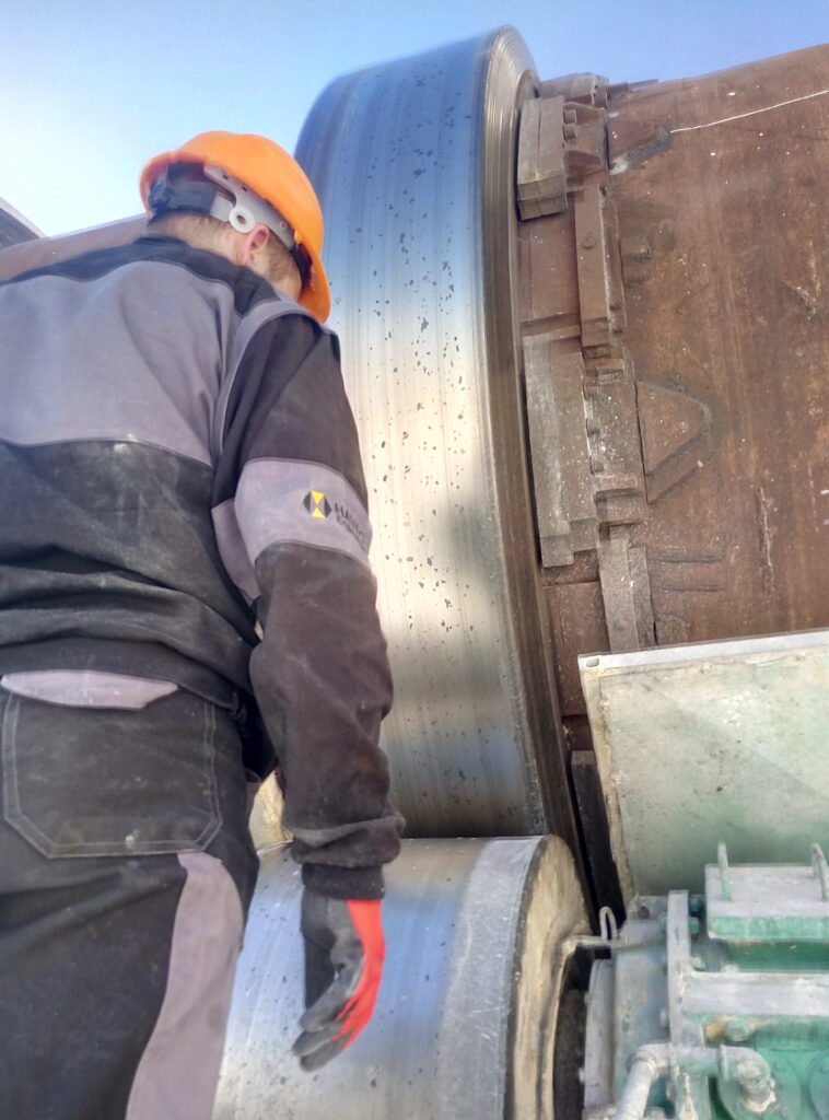 Engineer analyzing rotary kiln performance, standing next to the equipment to ensure proper operation and alignment.